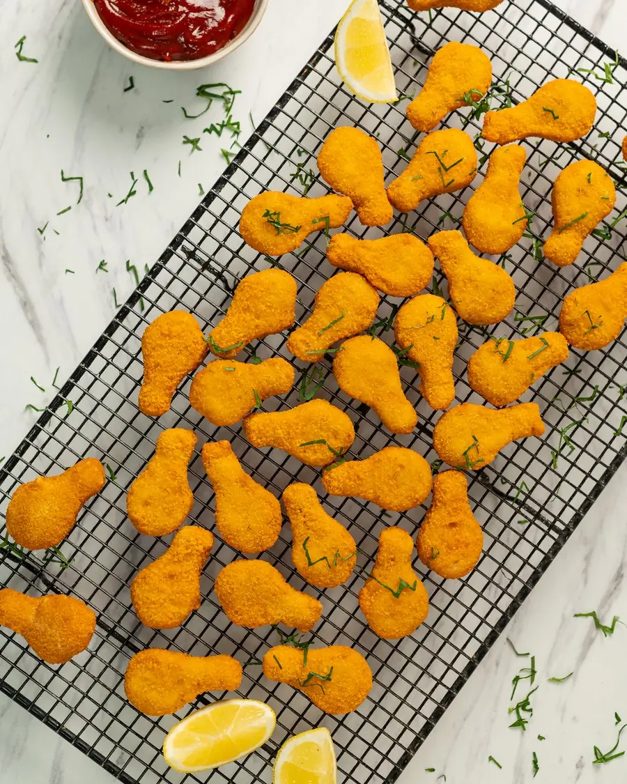 Formitas de pollo rebozadas BAS Frost doradas sobre una rejilla, con limón