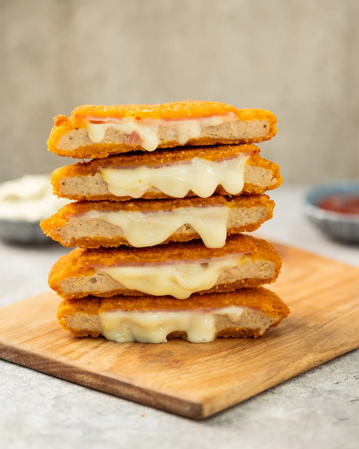 Medallones de pollo con jamón y queso BAS Frost apilados sobre una tabla, con el queso derretido